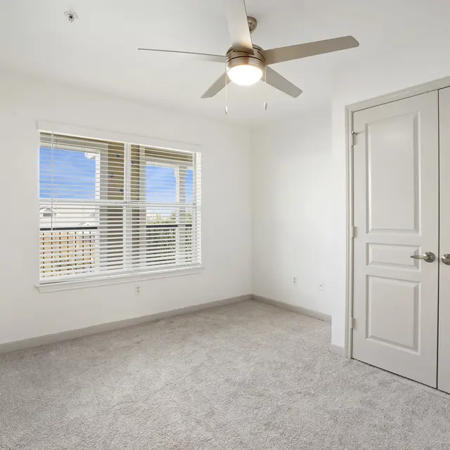 A room with a ceiling fan and a door.